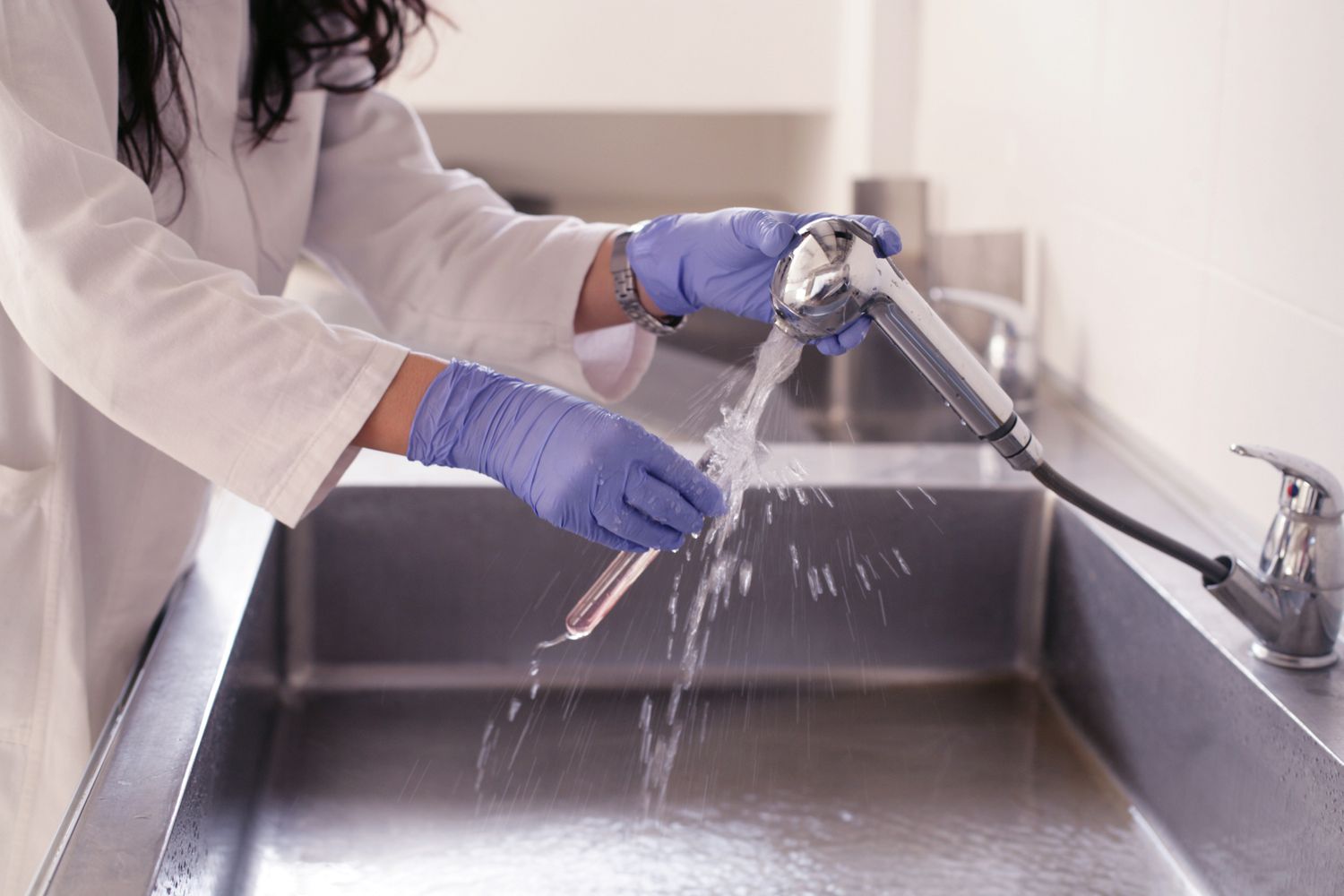 person cleaning laboratory glassware with safety gloves, science lab setting