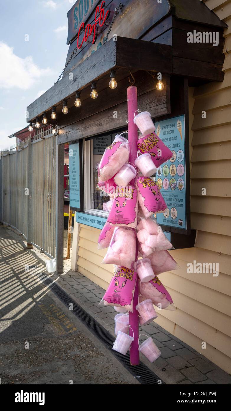 Pink candy floss on a stick being held up against a UK seaside pier Brighton background