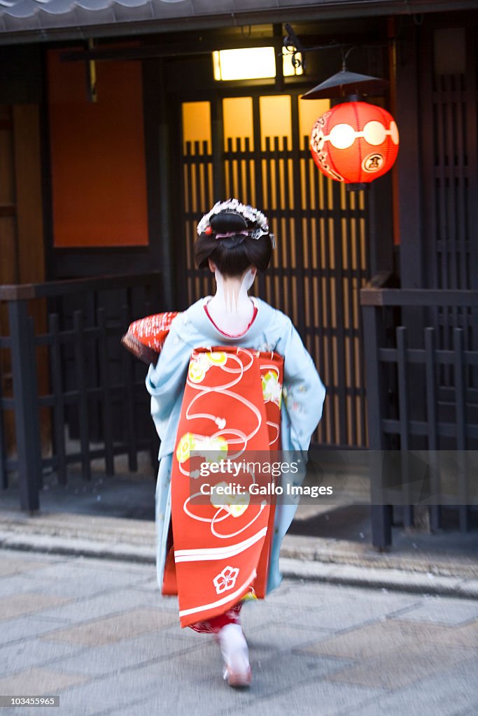 Close up of a Geisha walking in Gion district Kyoto, back view, traditional kimono, cinematic style