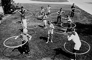 Black and white photo of kids playing with hula hoops in the 1950s