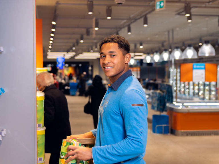 Albert Heijn employee stocking shelves smiling